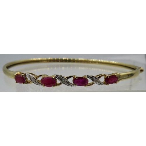 484 - A delicate 9ct yellow gold bangle set with four oval rubies. Each ruby approx 3mm x 5mm, intersperse... 