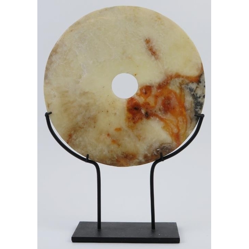 9 - A Chinese white and russet jade bi disc, Neolithic style, probably late 19th/20th century. Supported... 