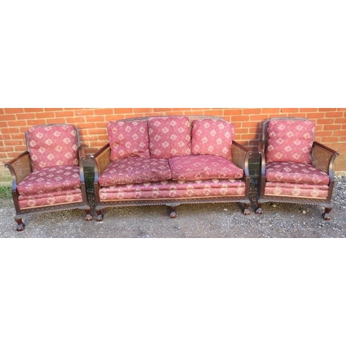 728 - An antique mahogany bergère three-piece suite, comprising a two-seater sofa and two armchairs, uphol... 