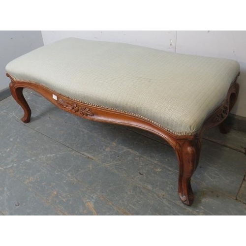 732 - A large 19th century walnut serpentine edged footstool, reupholstered in neutral material, the friez... 