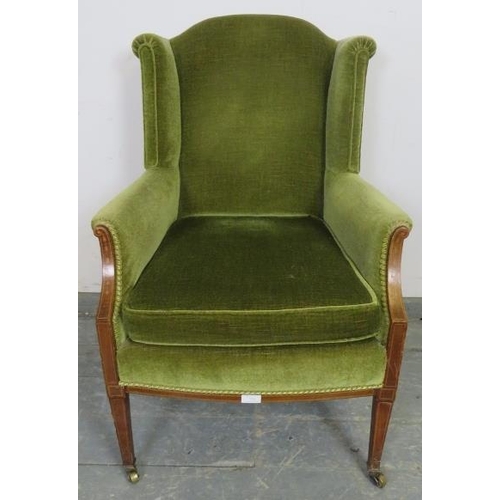 751 - An Edwardian mahogany wingback armchair, upholstered in green velvet material, strung with satinwood... 