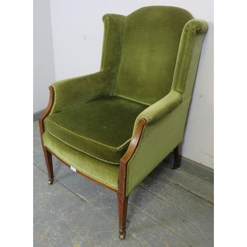 751 - An Edwardian mahogany wingback armchair, upholstered in green velvet material, strung with satinwood... 