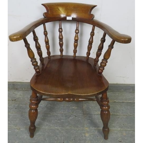 759 - A turn of the century elm and beech captain’s chair with turned spindles, on canted turned supports ... 