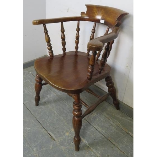 759 - A turn of the century elm and beech captain’s chair with turned spindles, on canted turned supports ... 