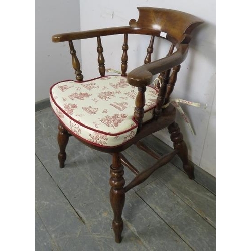 759 - A turn of the century elm and beech captain’s chair with turned spindles, on canted turned supports ... 