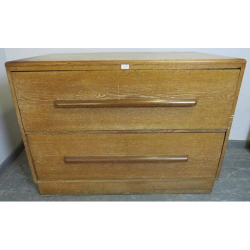 765 - An Art Deco limed oak chest housing two long and deep drawers with scalloped handles, on a plinth ba... 