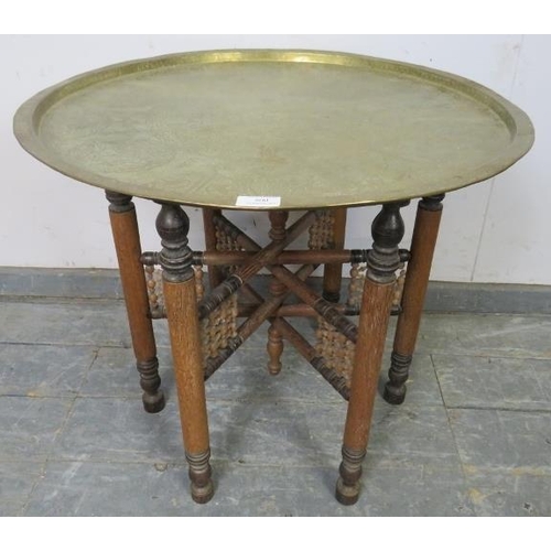 800 - A vintage Islamic Benares table, the intricately hand tooled brass tray top on a folding hardwood ba... 