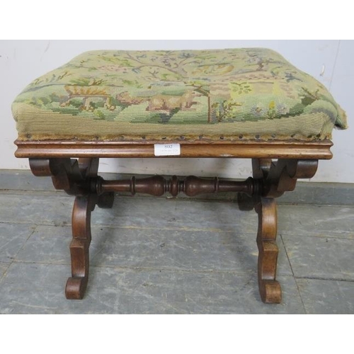 802 - A Victorian mahogany X-Frame tapestry footstool, on double scrolled supports with a turned middle st... 