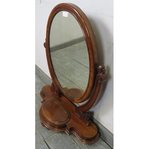 807 - A Victorian mahogany oval swing vanity mirror with scrolled uprights, on a shaped plinth base with c... 