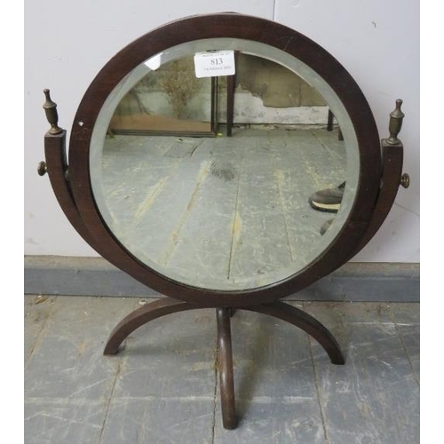 813 - An Edwardian mahogany double sided circular swing mirror with brass finials, having circular bevelle... 