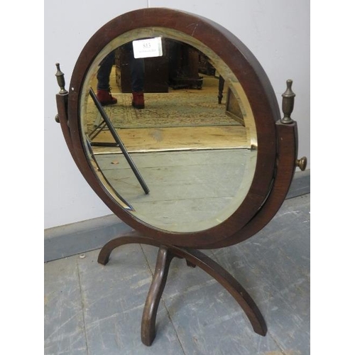 813 - An Edwardian mahogany double sided circular swing mirror with brass finials, having circular bevelle... 