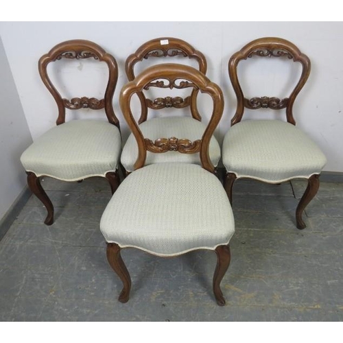 856 - A set of four Victorian walnut balloon back dining chairs, having carved and pierced backs, reuphols... 