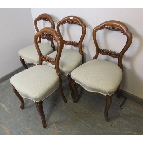 856 - A set of four Victorian walnut balloon back dining chairs, having carved and pierced backs, reuphols... 