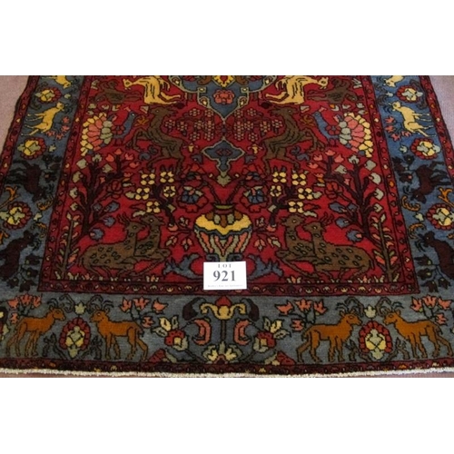 921 - A North West Persian Nahawand rug, blue on red ground with styalised animals. 195cm x 132cm (approx)... 