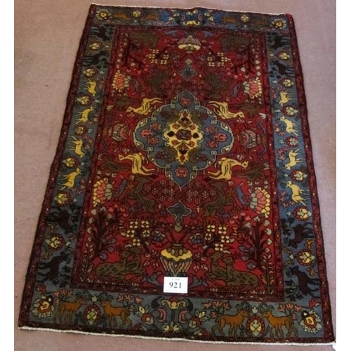 921 - A North West Persian Nahawand rug, blue on red ground with styalised animals. 195cm x 132cm (approx)... 