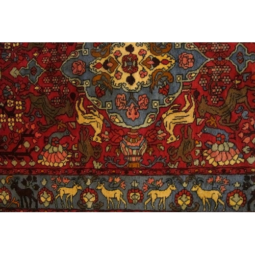 921 - A North West Persian Nahawand rug, blue on red ground with styalised animals. 195cm x 132cm (approx)... 