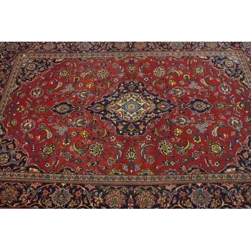 936 - Central Persian Kashan rug. Central motif and foliage on a red ground, with blue spandrels and borde... 