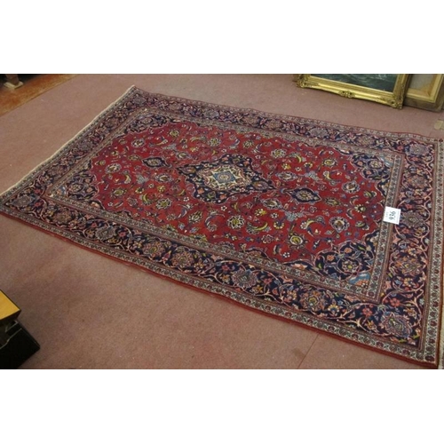 936 - Central Persian Kashan rug. Central motif and foliage on a red ground, with blue spandrels and borde... 