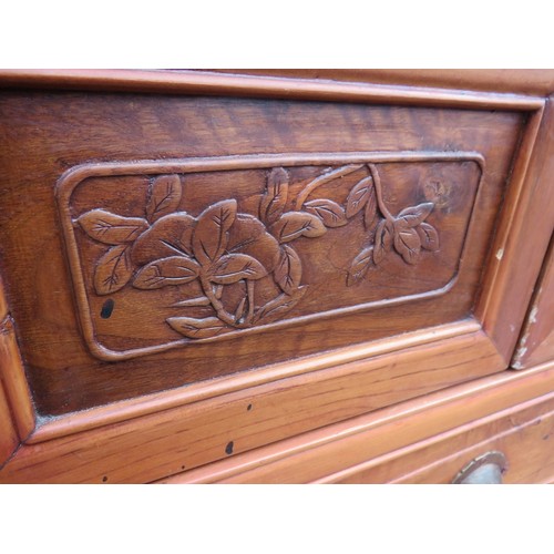 740 - A vintage Chinese elm kitchen cupboard, having carved and pierced decoration and slatted doors openi... 