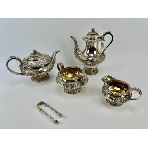 302 - A Georgian heavily embossed silver teapot, sugar bowl & cream jug, sitting on a pedestal base and de... 