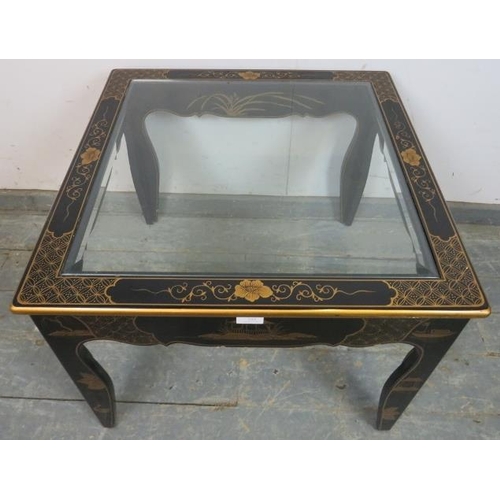 723 - A black and gold lacquer Chinoiserie side table, with inset bevelled glass top, on shaped supports. ... 