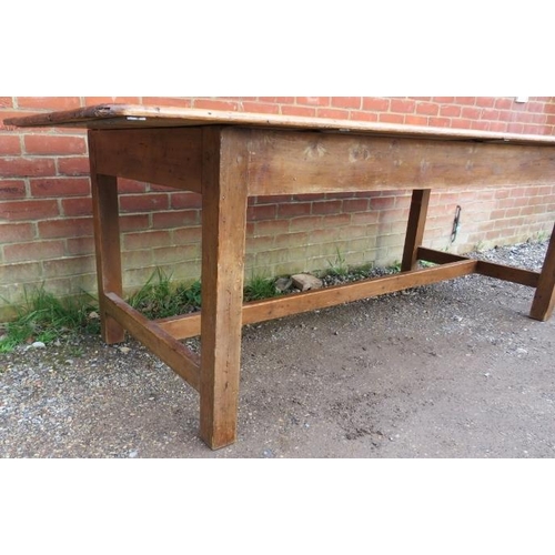 744 - An antique pine farmhouse kitchen table, of good colour and patina, on square supports with side str... 