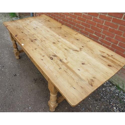 745 - An antique stripped pine farmhouse kitchen table, the planked top on baluster turned and block suppo... 