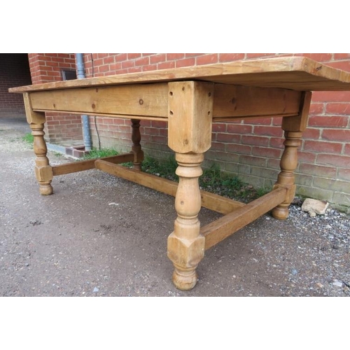 745 - An antique stripped pine farmhouse kitchen table, the planked top on baluster turned and block suppo... 