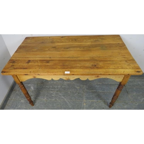 763 - An antique pine Continental kitchen table, the planked top above a shaped apron, on turned supports.... 