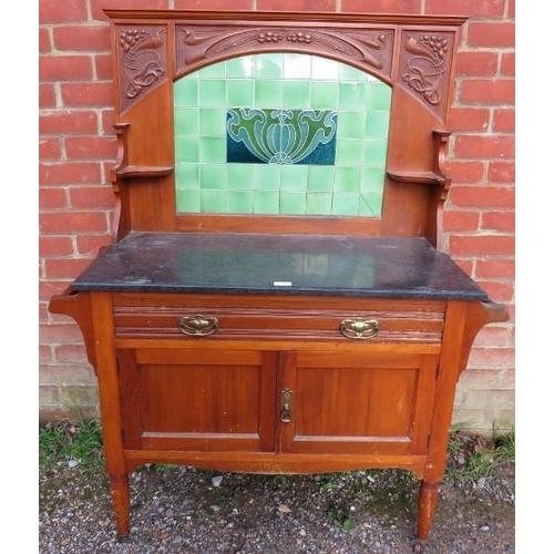 780 - An Art Nouveau walnut washstand, the relief carved rear gallery with inset green tiles, above a blac... 