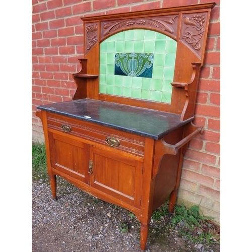 780 - An Art Nouveau walnut washstand, the relief carved rear gallery with inset green tiles, above a blac... 