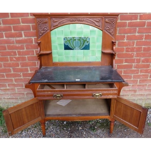 780 - An Art Nouveau walnut washstand, the relief carved rear gallery with inset green tiles, above a blac... 