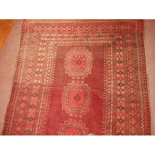 926 - An antique Persian rug, central panel with 3 motifs and deep borders on red ground, 210cm x 128cm.
C... 