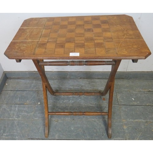 767A - An Edwardian walnut folding table with chessboard top, on curved supports with turned stretchers. 
H... 