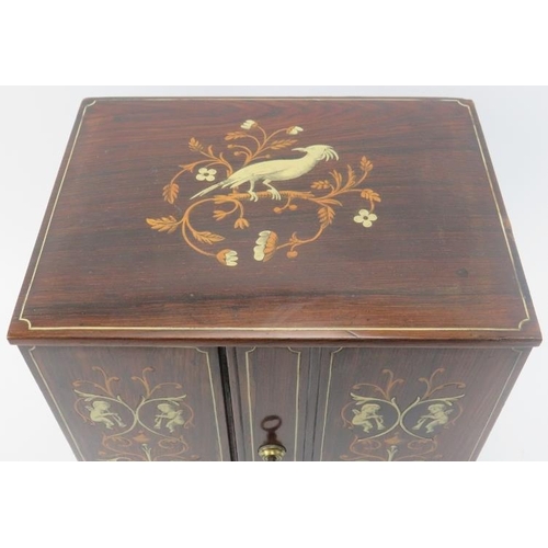 138 - Tobacconalia: An Edwardian rosewood and marquetry inlaid smokers cabinet. Decorated with cherubs, my... 