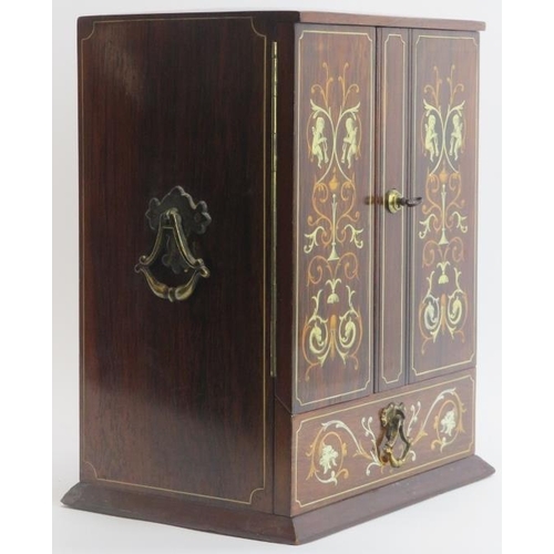 138 - Tobacconalia: An Edwardian rosewood and marquetry inlaid smokers cabinet. Decorated with cherubs, my... 