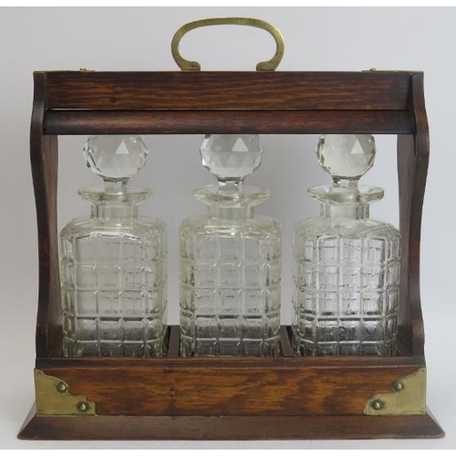 149 - A brass mounted oak tantalus with three glass decanters, late 19th/early 20th century. 34.8 cm lengt... 