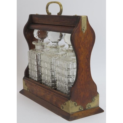 149 - A brass mounted oak tantalus with three glass decanters, late 19th/early 20th century. 34.8 cm lengt... 