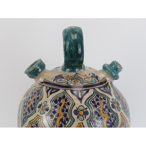 23 - A large Moroccan tin glazed pottery water decanter jug. Modelled with a loop handle and two spouts (... 