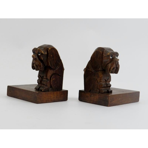 34 - A pair of Black Forest dog bookends, early 20th century. The carved wood seated dogs modelled with g... 