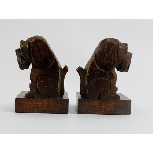 34 - A pair of Black Forest dog bookends, early 20th century. The carved wood seated dogs modelled with g... 