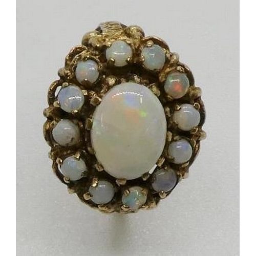 376 - An opal cluster ring, testing as 9ct gold, the central oval opal cabochon measuring 9 x 7mm. 3.9gms.... 