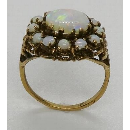 376 - An opal cluster ring, testing as 9ct gold, the central oval opal cabochon measuring 9 x 7mm. 3.9gms.... 