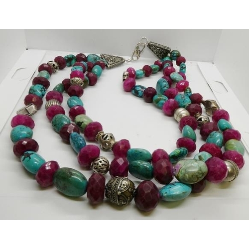 379 - A large triple row reconstituted turquoise, ruby and white metal bead necklace, with a series of gra... 