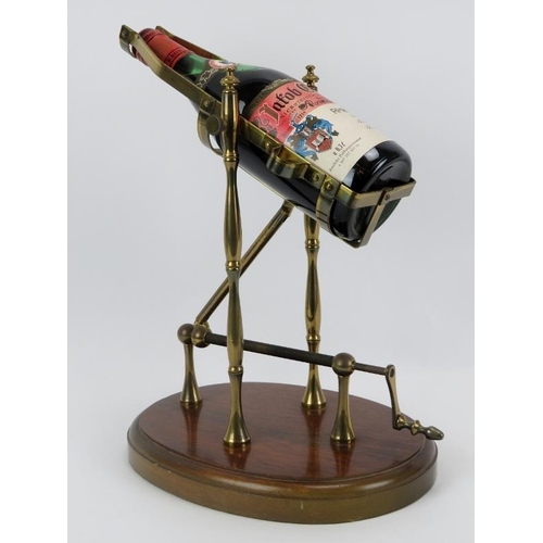 49 - A brass mechanical wine decanting cradle. Supported on an oval oak plinth. Bottle of Jacob Gerhardt ... 