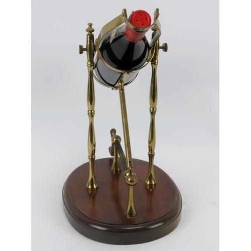 49 - A brass mechanical wine decanting cradle. Supported on an oval oak plinth. Bottle of Jacob Gerhardt ... 