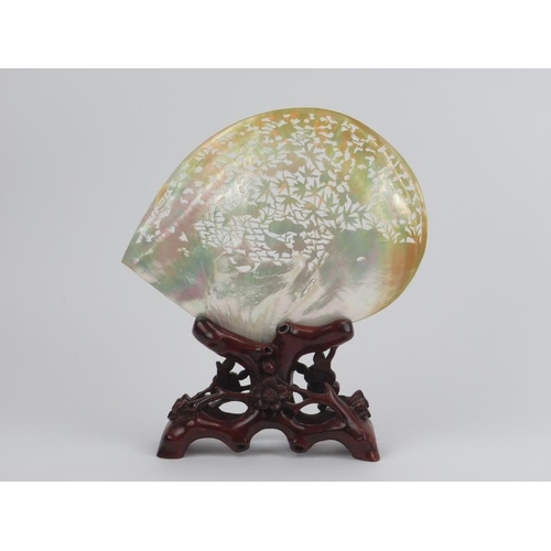 79 - A large Chinese carved and pierced mother of pearl shell mounted on a carved wood stand, mid/late 20... 