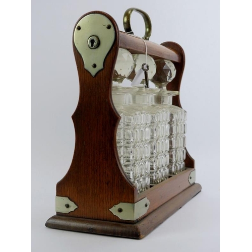 88 - An oak tantalus with three glass decanters, late 19th/early 20th century. 34.7 cm length, 31.5 cm he... 