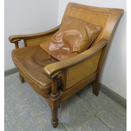 702 - An antique style fruitwood armchair, having double skin bergère back and sides, with loose cushions ... 