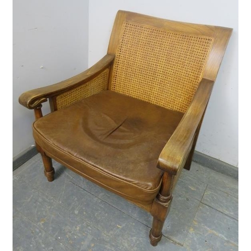 702 - An antique style fruitwood armchair, having double skin bergère back and sides, with loose cushions ... 